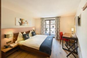 a hotel room with a bed and a desk and a window at Hotel Cervo in Sils Maria