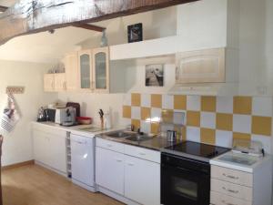 a kitchen with white cabinets and a sink and a stove at Gîte Proche du Bassin d'Arcachon in Mios