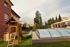 un parque infantil con invernadero junto a un edificio en Pension Viola, en Domažlice