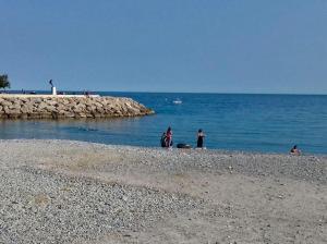 a group of people standing on a beach near the water at Maison Menton in Menton