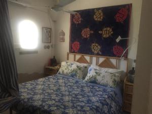 sypialnia z łóżkiem z kołdrą na ścianie w obiekcie Casa Tortuca w mieście Lampedusa