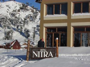un hombre de pie junto a una señal en la nieve en Hotel Nitra-Caviahue en Caviahue