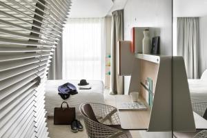 Cette chambre comprend un bureau, des chaises et un lit. dans l'établissement Okko Hotels Paris Porte De Versailles, à Paris