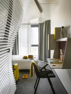 - une chambre avec un lit, une chaise et une fenêtre dans l'établissement Okko Hotels Paris Porte De Versailles, à Paris