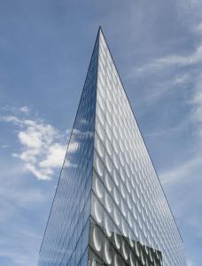 un grand bâtiment en verre contre un ciel bleu dans l'établissement Okko Hotels Paris Porte De Versailles, à Paris