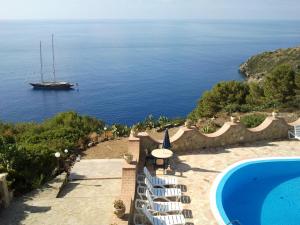 a pool with chairs and a boat in the water at Hotel Diana in Ustica