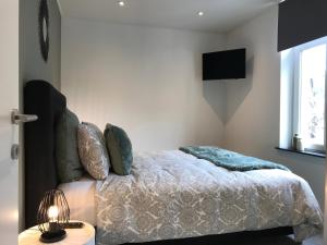 een slaapkamer met een bed en een televisie aan de muur bij Le Coin Cocoon Inn in Aywaille