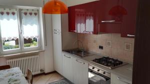 a kitchen with red cabinets and a stove and a window at Villa Ginestra in Molveno