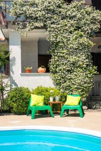 two green chairs sitting next to a swimming pool at Apartment with private pool and arbor in Malinska