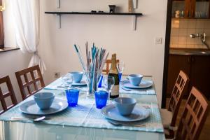 a table with plates and cups and a bottle of wine at Apartment with private pool and arbor in Malinska