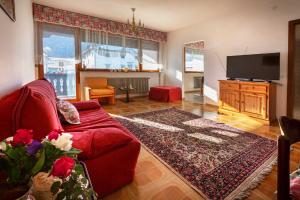 un soggiorno con divano rosso e TV a schermo piatto di Albergo Diffuso "Col Gentile" Socchieve a Priuso