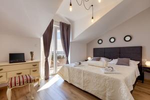 a white bedroom with a large bed and a window at Apartments Solmar in Podstrana +55 photos