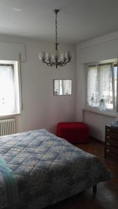 a bedroom with a bed and a chandelier and two windows at Villa Ginestra in Molveno