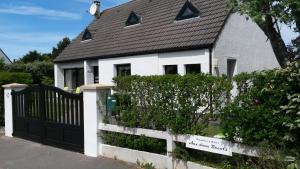 a white house with a black gate and a fence at Aux doux Becots - Bed & Breakfast in Hardelot-Plage