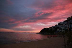 a sunset on a beach with a red sky at Canyelles Platja in Roses