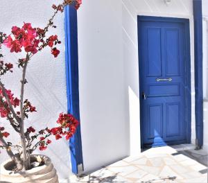 a blue and white vase filled with flowers next to a blue door at Bungalows Marina in Naousa