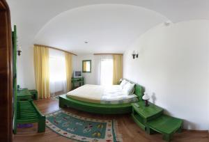 a bedroom with a green bed and a couch at Pension Irina in Arefu