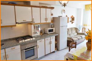 een keuken met witte kasten, een koelkast en een bank bij Apartamento Paseo del Puerto 2 in Finisterre