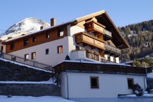 a building in the snow with a mountain in the background at Pension Bergsee in Sölden