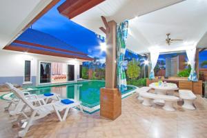 a house with a swimming pool and white chairs at Victoria Villa in Na Jomtien