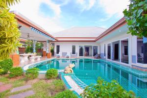 a dog sitting next to a swimming pool in a house at Victoria Villa in Na Jomtien