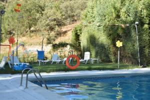 a swimming pool with chairs and a swing and a playground at Cabañas Camping Sierra de Peñascosa in Peñascosa