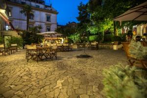 un patio al aire libre con mesas, sillas y sombrillas en Hotel Victoria Maiorino, en Cava deʼ Tirreni