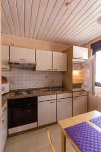 eine Küche mit weißen Schränken und einem schwarzen Herd mit Backofen in der Unterkunft Ferienwohnung Arnold in Burkardroth