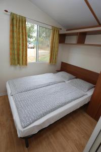 Cama en habitación con ventana en Mobile Homes Comfort CAPRI Bijela Uvala, en Poreč