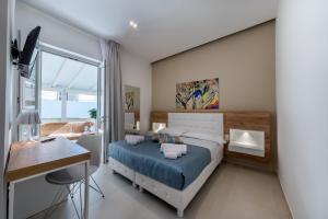 a bedroom with a bed and a desk and a window at Artemide Hotel in San Vito lo Capo