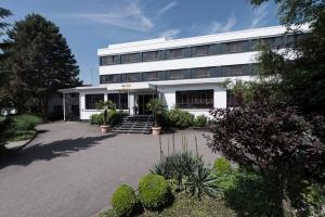 a white building with a lot of plants in front of it at ibis Styles Offenburg City in Offenburg