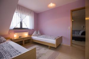 Duas camas num quarto com paredes roxas e um espelho em Ferienwohnung Arnold em Burkardroth