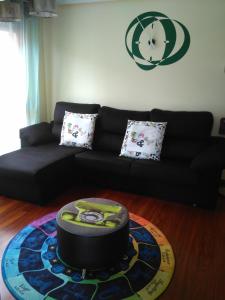 a living room with a black couch and a clock on the wall at Apartamento La Gloria in Gibaja