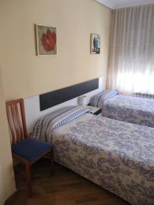 a hotel room with two beds and a chair at Hostal Becares in Palencia