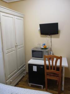 Zimmer mit einem Schreibtisch, einer Mikrowelle und einem TV. in der Unterkunft Hostal Becares in Palencia