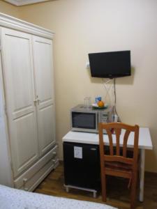 a room with a desk with a microwave and a television at Hostal Becares in Palencia