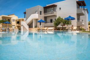 a large swimming pool with blue umbrellas in front of a building at IRINI STALOS Apartments in Stalos