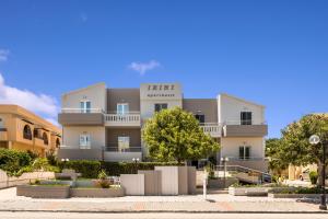 a tall white building with trees in front of it at IRINI STALOS Apartments in Stalos