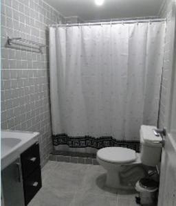 y baño con aseo y cortina de ducha. en Spazio Itaúna Pousada, en Saquarema