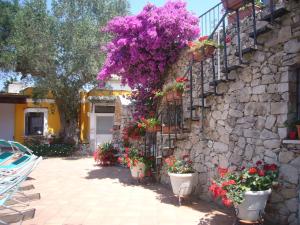 a stone wall with flowers and plants in pots at Villa Vacanze Paradiso - Oasi di Tranquillità con Piscina e Giardino a 10 min dal mare in Neviano