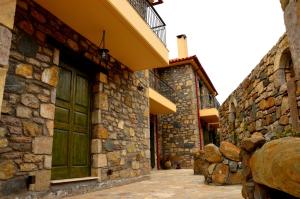 a building with a green door and a stone wall at Messana in Messini