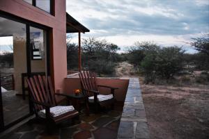 a patio with two chairs and a table on a house at Cheetah View Lodge in Otjiwarongo