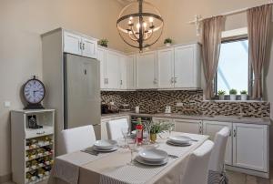 a kitchen with a table with white cabinets and a clock at Admiral's House in Halki
