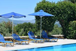 a group of blue chairs and umbrellas next to a swimming pool at Aspalathos Villas in Fílippos
