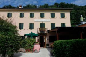 ein Gebäude mit grünen Fensterläden und einem Gebäude mit einem Tisch in der Unterkunft Locanda da Bepi in Marano di Valpolicella