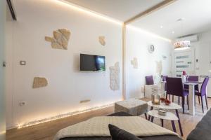 a living room with a couch and a tv on a wall at Apartments Lavanda & Rozmarin in Split