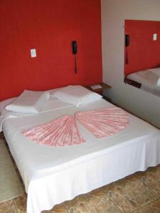 a large white bed with a pink blanket on it at Previato Hotel in Curitiba