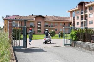 una persona che cavalca uno scooter attraverso un cancello di Airone Apartment a Novara