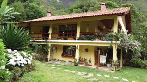 een geel huis met een tuin ervoor bij Pousada Ribeirao da Floresta in Lumiar