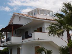 a white house with a balcony and palm trees at Sulle tracce di Montalbano in Ragusa